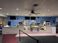 the inside of a movie theater with a counter and a ceiling fan