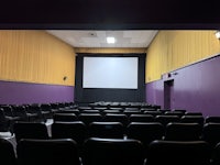 a movie theater with purple chairs and a projector screen