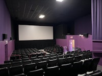 a movie theater with purple walls and black chairs